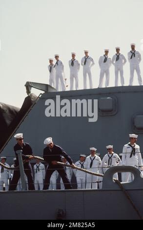 Gli equipaggi si trovano in cima a una torretta da 16 pollici a bordo della corazzata USS NEW JERSEY (BB 62) mentre un equipaggio di lavoro gestisce le linee di ormeggio. Il NEW JERSEY sta ritornando al porto di casa dopo 11 mesi in mare. Base: Naval Air Station, Long Beach Stato: California (CA) Paese: Stati Uniti d'America (USA) Foto Stock