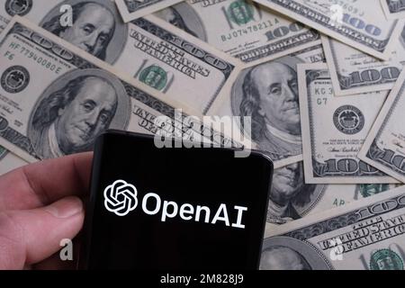 Logo OPENAI visto su smartphone e dollari sfocati sullo sfondo. Concetto. Stafford, Regno Unito, 11 gennaio 2023 Foto Stock