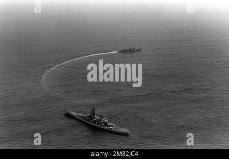 Una vista elevata del quarto di porto della nave da guerra USS IOWA (BB-61) in primo piano con la fregata missilistica guidata USS FLATLEY (FFG-21) che circling. Paese: Sconosciuto Foto Stock