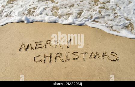 Buon Natale scritto a mano in sabbia su una bella spiaggia Foto Stock