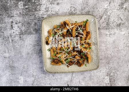 Melanzane e pasta di carne con erbe su un piatto quadrato su sfondo scuro. Vista dall'alto, a pianta piatta» Foto Stock