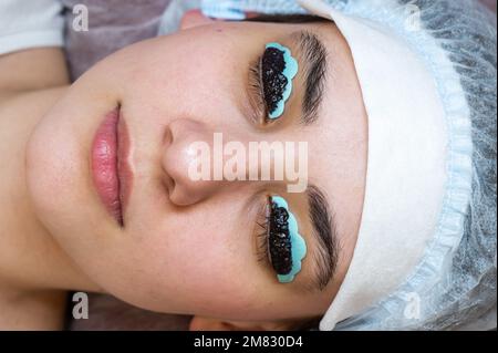 Primo piano ritratto di una donna sulla procedura di laminazione e tintura delle ciglia. Trucco permanente. Foto Stock