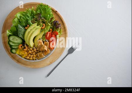 Vista dall'alto, Un piatto di verdure sane insalata biologica mescolato con tofu alla griglia, ceci, noci, pomodori, cetrioli, scivoli di avocado, spinaci e verdi Foto Stock