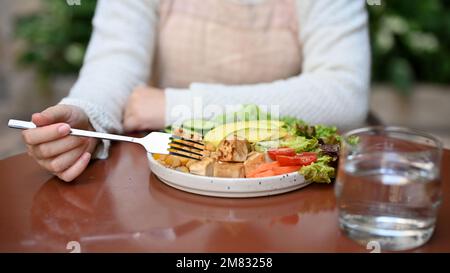 Immagine ritagliata, Una donna è in dieta, avendo la sua colazione sana, mangiare Buddha insalata ciotola. concetto di cibo vegano e a base vegetale Foto Stock