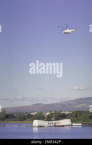 Un elicottero anti-sottomarino Squadron 2 (HS-2) SH-3H Sea King vola sopra il memoriale USS ARIZONA (BB-39). Una bandiera vola a mezza altezza in cima al memoriale per commemorare il 43rd° anniversario dell'attacco giapponese. Base: Pearl Harbor Stato: Hawaii (HI) Paese: Stati Uniti d'America (USA) Foto Stock