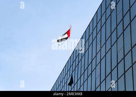 Bandiera che sventola in cima all'edificio moderno, simbolo nazionale degli Emirati Arabi Uniti. Giornata Nazionale e giornata della bandiera degli Emirati Arabi Uniti. La bandiera degli Emirati Arabi Uniti su Foto Stock