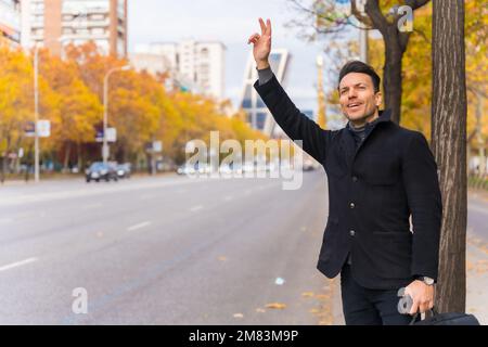 Un uomo d'affari caucasico di mezza età che salutava un taxi alzando la mano per andare al lavoro Foto Stock