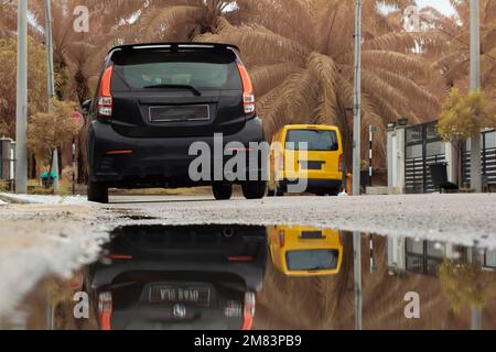 ristagnante piscina d'acqua scena dopo la pioggia al sobborgo strada asfaltata Foto Stock