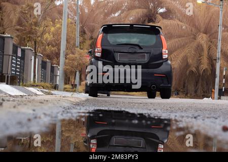 ristagnante piscina d'acqua scena dopo la pioggia al sobborgo strada asfaltata Foto Stock