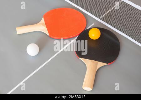 Due racchette da ping pong e palle su un tavolo grigio Foto Stock