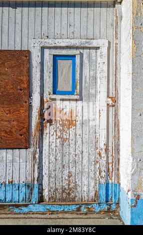 Porta con vernice bianca e blu peeling su un edificio abbandonato in legno Foto Stock
