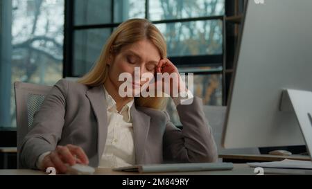 Donna di mezza età adulta stanca pigra lavoratrice manager annoiata al lavoro progetto on-line in computer in ufficio caucasico malato maturo Foto Stock