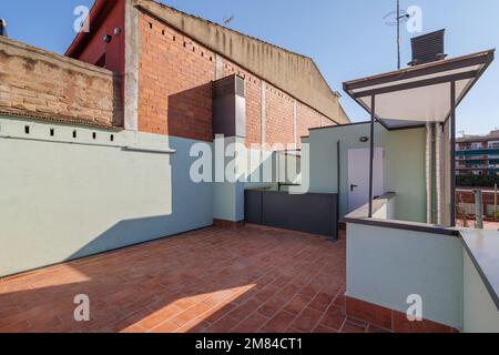 Terrazza aperta al secondo piano con pavimento in mattoni rossi. Parte della terrazza con recinzione di ringhiere leggere confina con il muro di grande casa in mattoni. Da esso potete Foto Stock