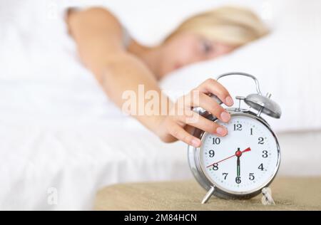 Non può essere che ora già... Una giovane donna che mette la sua sveglia fuori al mattino. Foto Stock