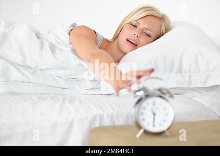 Non può essere che ora già... Una giovane donna che mette la sua sveglia fuori al mattino. Foto Stock