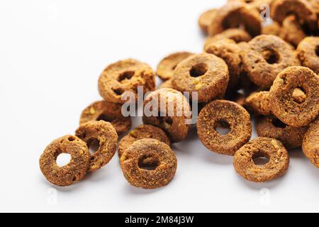 Granuli di foraggio secco a forma di anelli per cani su fondo bianco. Cibo sano per cani Foto Stock