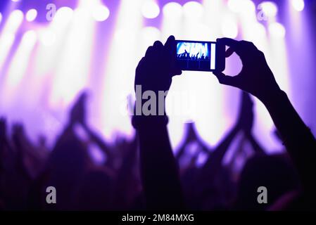 Cattura l'attimo. Una persona che filma la propria band preferita con un telefono con fotocamera. Foto Stock