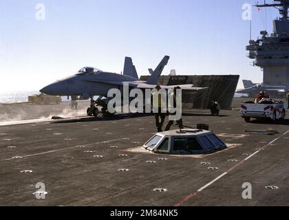 Un ispettore aereo di squadrone guarda come un F/A-18A Hornet Aircraft di Strike Fighter Squadron 125 è posizionato su una catapulta durante le operazioni di volo a bordo della portaerei nucleare USS CARL VINSON (CVN-70). Dietro l'aeromobile è presente un deflettore a getto rialzato e in primo piano è presente la sala di controllo per il sistema di controllo catapulta integrato. Paese: Oceano Pacifico (POC) Foto Stock