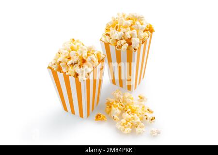 Due cestelli in cartone a strisce gialle bianche con gustosi popcorn al formaggio, isolati su sfondo bianco. Concetto di film, cinema e intrattenimento. Foto Stock