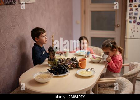 Tre bambini cenano insieme in cucina. Foto Stock