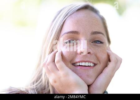 Ha una disposizione soleggiata. Ritratto di una bella giovane donna all'aperto. Foto Stock