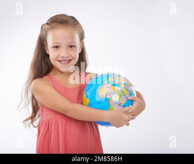 Tiene il futuro nelle sue mani. Una bambina carina che tiene un globo e sorride alla macchina fotografica. Foto Stock