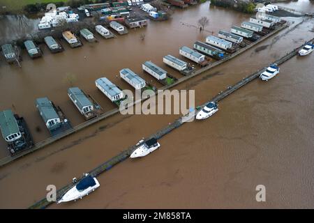 Kempsey, Worcestershire, 12 gennaio 2023 - le carovane natalizie presso il campo ricreativo di Seaborne a Kempsey, Worcestershire sono state abbandonate dall'acqua alluvionale dopo che il fiume Severn ha fatto esplodere le sue sponde. Le carovane statiche rialzate hanno ora la vista di un grande specchio d'acqua e di imbarcazioni da diporto ormeggiate fuori portata. Si prevede che il livello del fiume raggiunga il picco il sabato. Credito: Interrompi stampa Media/Alamy Live News Foto Stock