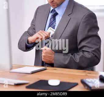 Tenere i suoi beni vicino al petto. un uomo d'affari che mette i soldi nella sua tasca blazer. Foto Stock