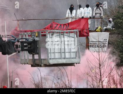 Erkelenz, Germania. 12th Jan, 2023. Gli attivisti infiammano i pirotecnici il secondo giorno dello sfratto nella frazione lignita di Lützerath occupata da attivisti climatici. L'azienda energetica RWE vuole scavare il carbone che si trova sotto Lützerath - a questo scopo, il borgo sul territorio della città di Erkelenz presso l'opencast lignite miniera Garzweiler II è da demolire. Credit: Rolf Vennenbernd/dpa/Alamy Live News Foto Stock