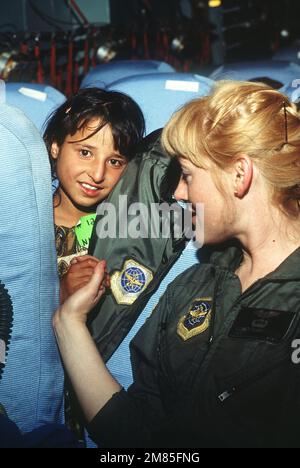 Un membro dello Squadrone di evacuazione Aeromedica del 2nd del comando militare dell'Airlift Command comforta un bambino afghano a bordo di un aereo Starlifter C-141b. La bambina è uno dei 25 civili afghani trasportati al Centro medico regionale dell'aeronautica statunitense di Weisbaden, Germania occidentale, per un trattamento medico specializzato in seguito a lesioni subite a seguito della guerra civile in Afghanistan. I pazienti saranno successivamente evacuati negli ospedali in Europa e negli Stati Uniti per l'assistenza medica donata. Paese: Sconosciuto Foto Stock