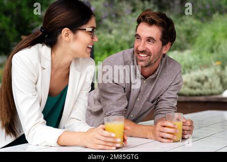 Un paio di colleghi felici che parlano in piedi alla finestra dell'ufficio con il succo. Foto Stock