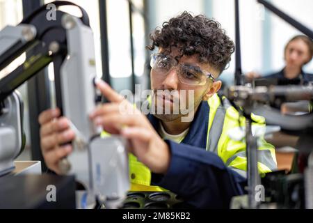 Il tecnico impara la teoria di base su come eseguire la manutenzione e programmare il braccio del robot nell'aula di formazione Foto Stock