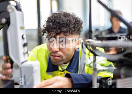 Il tecnico impara la teoria di base su come eseguire la manutenzione e programmare il braccio del robot nell'aula di formazione Foto Stock