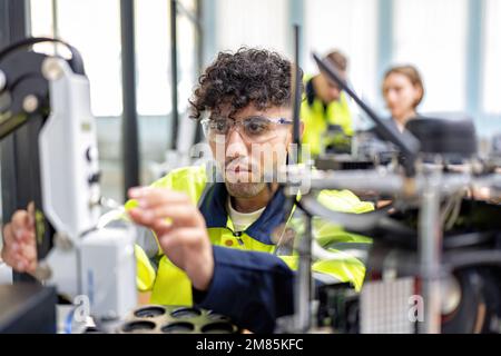 Il tecnico impara la teoria di base su come eseguire la manutenzione e programmare il braccio del robot nell'aula di formazione Foto Stock