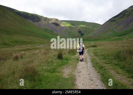 Uomo che cammina su un sentiero per Cautley Spout Waterfall & Crag nelle Howgill Fells vicino Sedbergh nel Yorkshire Dales National Park, Inghilterra, Regno Unito. Foto Stock