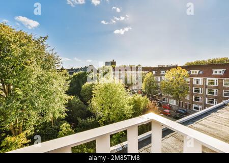 un balcone con alberi e case sullo sfondo, preso da una finestra di un appartamento che si affaccia sulla strada sottostante Foto Stock