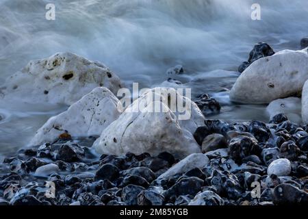 Rocce sulla costa del Sussex, con una lunga vista delle onde che le attraversano Foto Stock