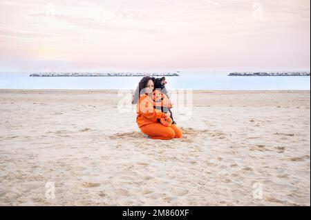 Halloween cane vestito come una zucca sulla spiaggia. Black Cocker Spaniel in abiti festosi gioca con il suo proprietario. Autunno terrapieno e una bella passeggiata. Sentimenti teneri con gli animali domestici Foto Stock