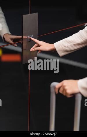 vista ritagliata della donna che preme il pulsante di chiamata ascensore in hotel, immagine stock Foto Stock