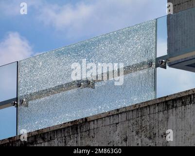 ringhiera balaustra in vetro frantumata. vetro di sicurezza laminato. facciata in pietra. fogli di sicurezza laminati temprati rotti. concetto di costruzione. cielo blu Foto Stock