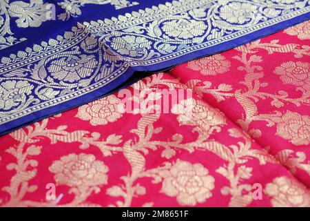 Varietà artistica tonalità tonalità tonalità tonalità colori ornamenti motivi, primo piano vista di stacked saris o sarees in mostra di negozio al dettaglio. Foto Stock