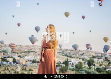 Donna turistica che guarda mongolfiere in Cappadocia, Turchia. Buon viaggio in Turchia concetto. Donna in cima a una montagna che gode di una vista meravigliosa Foto Stock