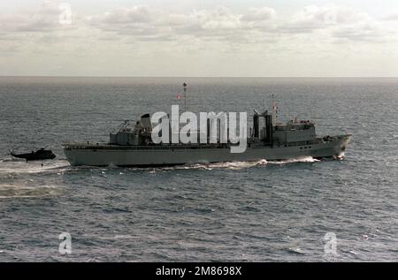 Una vista aerea a dritta della nave canadese di rifornimento HMCS PROTECTEUR (AOR-509) in corso durante l'esercizio NATO Northern Wedding '86. Un elicottero britannico Royal Navy Sea King è a poppa della nave che utilizza un sonar da immersione AQS-13 durante una pattuglia anti-sottomarina. Soggetto operativo/Serie: NORTHERN WEDDING '86 Paese: Oceano Atlantico (AOC) Foto Stock