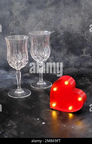 Due bicchieri da bibita con cuore illuminato su sfondo scuro Foto Stock