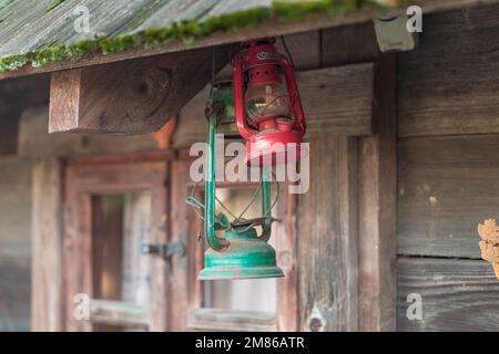 Una vecchia lampada a cherosene appesa ad una trave o finestra di legno. Foto Stock