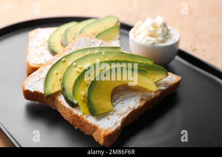 Piatto di gustosi panini con formaggio cremoso e avocado su sfondo colorato, primo piano Foto Stock