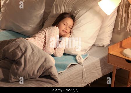 Bambina che dorme su un cuscino riscaldante elettrico in camera da