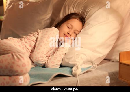 Bambina che dorme su un cuscino riscaldante elettrico in camera da letto di  notte Foto stock - Alamy