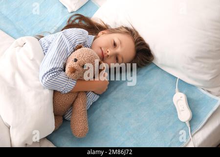 Bambina con giocattolo sdraiata sulla piastra riscaldante elettrica in  camera da letto Foto stock - Alamy