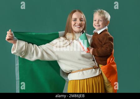 Bella donna con il suo piccolo figlio e bandiera d'Irlanda su sfondo verde Foto Stock